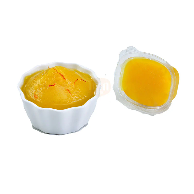 A white bowl filled with rich, golden-yellow Badam Halwa garnished with strands of saffron, alongside a transparent cup of liquid Badam Halwa, showcasing its smooth and inviting texture